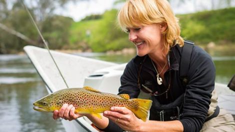 A woman in a boat holding a trout